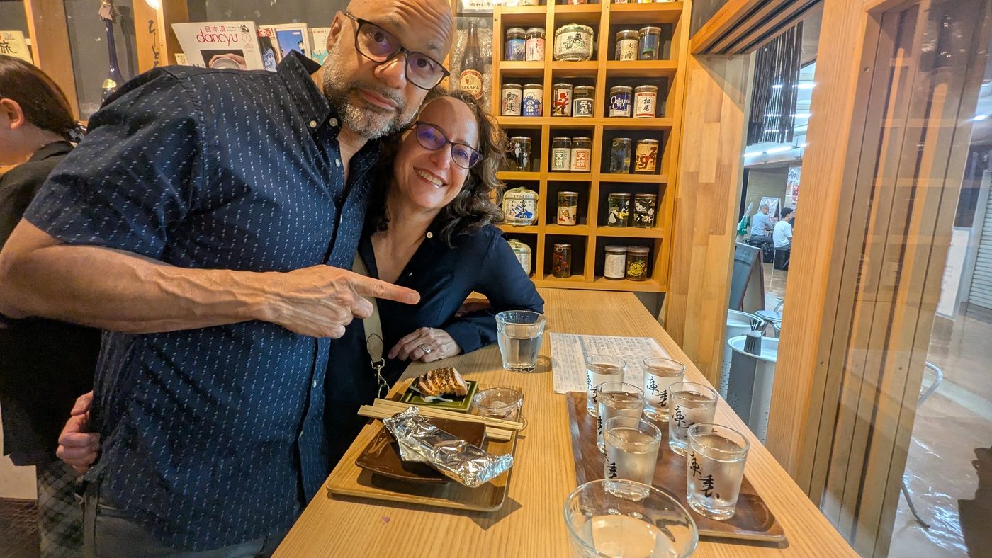 A couple tasting sake at a standing bar